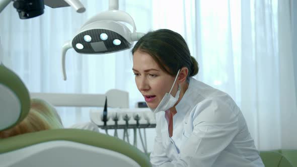 Dentist Directs a Lamp at the Girls Mouth and Looks at Her Teeth.