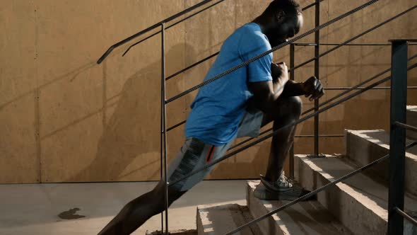 Fit man stretching legs, doing lunge exercise on stairs
