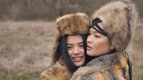 close-up of two loving Asian young women in ethnic clothes embracing posing in the steppe in nature.