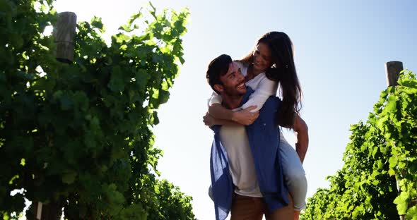 Man giving piggy back to woman in the wine farm