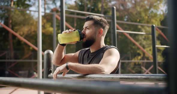 Athlete Relaxing and Drinks Water From the Bottle After an Intense Workout