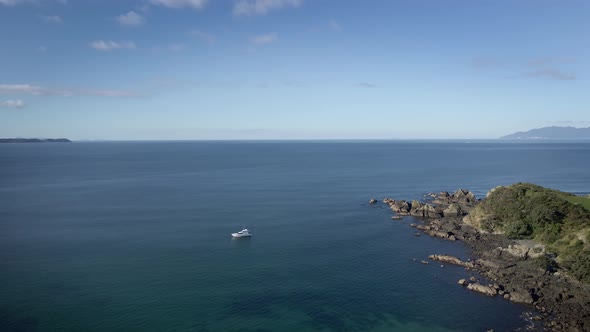 Yacht Adrift In Calm Blue Sea In Tawharanui Peninsula In New Zealand. wide aerial