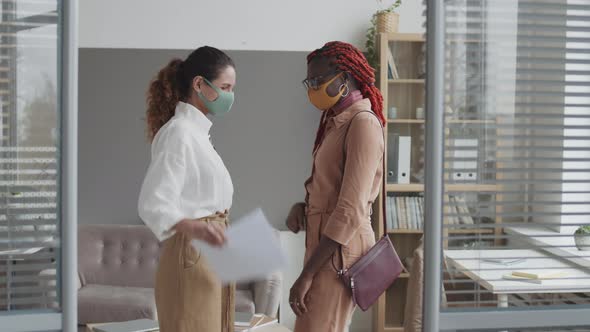 Two Female Coworkers Wearing Masks Greeting Each Other