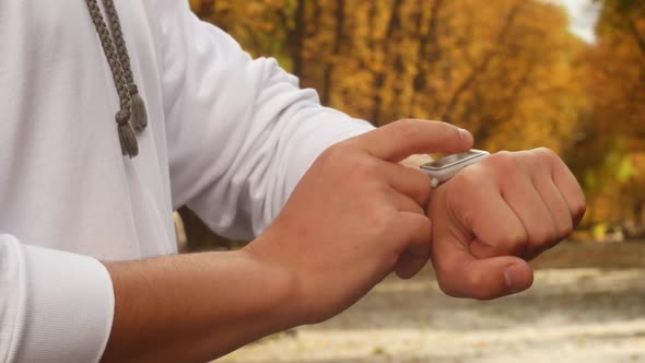 Man Using Smartwatch In Autumn Park