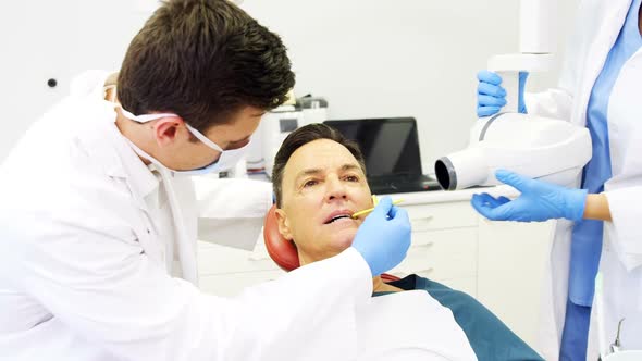 Dentist examining a male patient with tool