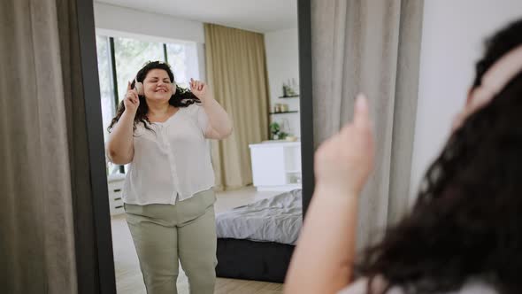 Brunette in Headphones Dances Looking at Mirror Reflection