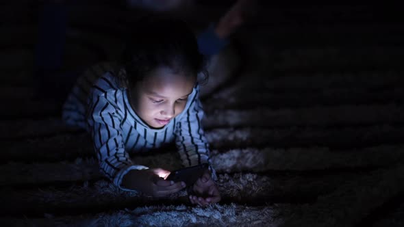 Child Girl Laying on Floor Using Smart Phone at Night