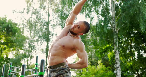 Sporty Young Man Bending Sideways and Warming Up Preparing His Muscles for Workout Outdoor