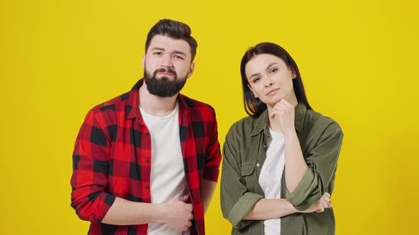 Caucasian Young Stylish Couple Looking at Camera on Yellow Background and Suddenly Guess Reaction of