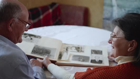 Top View, Loving Elderly Man with His Smiling of Wife Enjoys Family Memories While Watching Photos