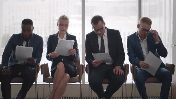 Diverse Applicants Waiting for Job Interview Sitting in Line and Reading Cv