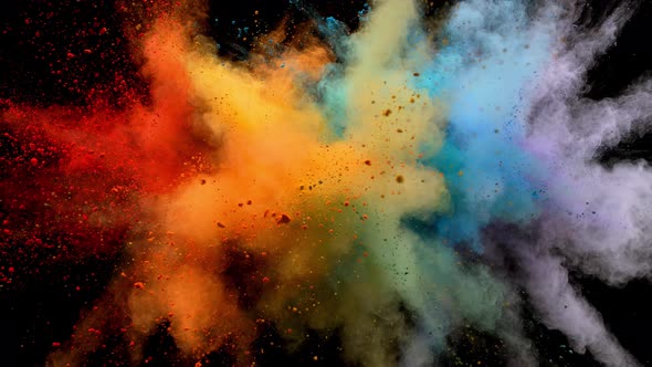 Colorful powder/particles fly after being exploded against black background. Slow Motion.