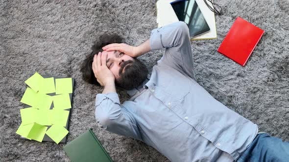 Young Man Surrounded By Computer and Documents Very Tired and Exhausted