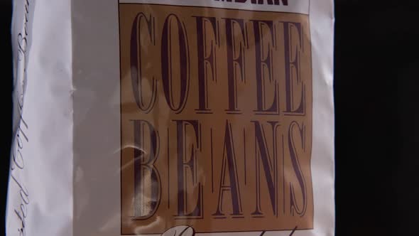 Close-up of a pack of coffee, the camera flies around. Parallax effect. Slow motion. Coffee beans