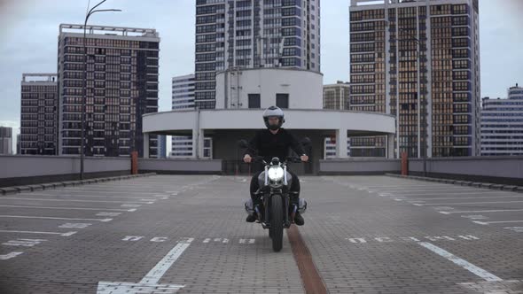 Man Riding Scrambler Motorbike on Top of the Multilevel Parking in City