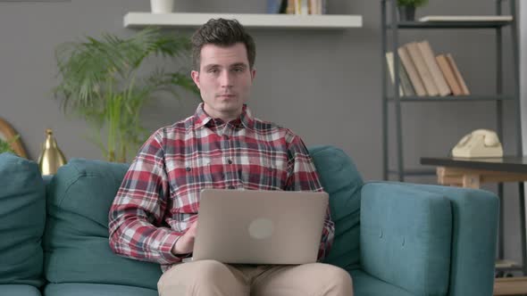 Man with Laptop Showing Thumbs Up on Sofa