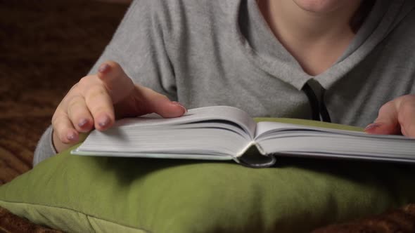 Beautiful Girl Reads a Book Comfortably While Lying in Bed