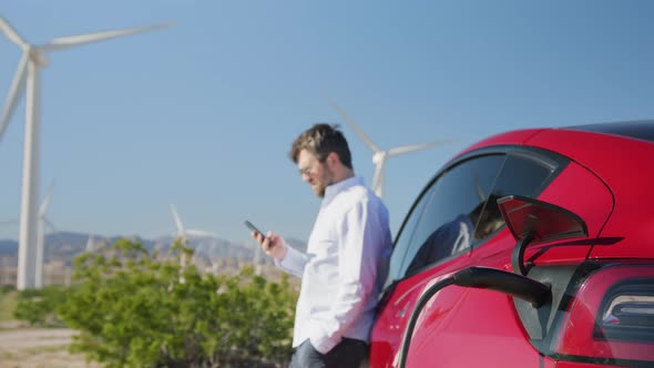 Futuristic Concept Professional Male Waiting at Electric Vehicle Windmills