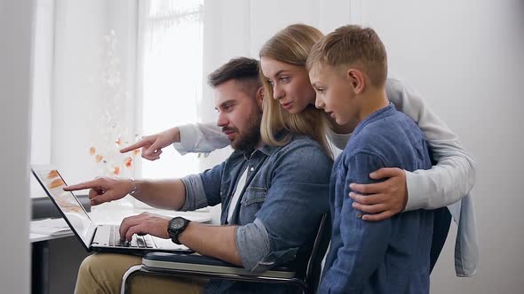 Family Watching on Computer and Discussing Seen on Screen Near Big Window