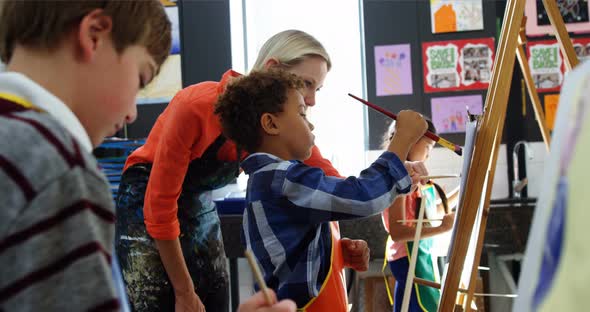 Teacher assisting schoolboy in drawing class