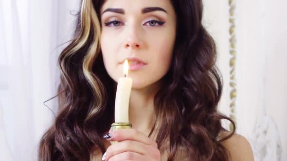 Young Brunette Woman Snuffs Off a Candle