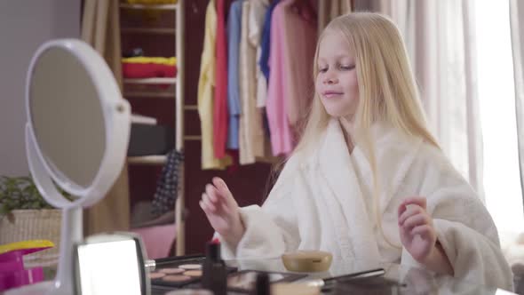 Middle Shot of Charming Blond Caucasian Girl Admiring Her Reflection in Mirror and Doing Makeup