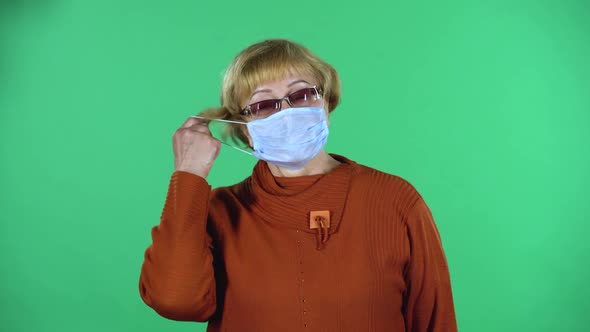 Portrait of Senior Woman Takes Off Her Medical Disposable Mask and Takes a Deep Breat, Isolated Over