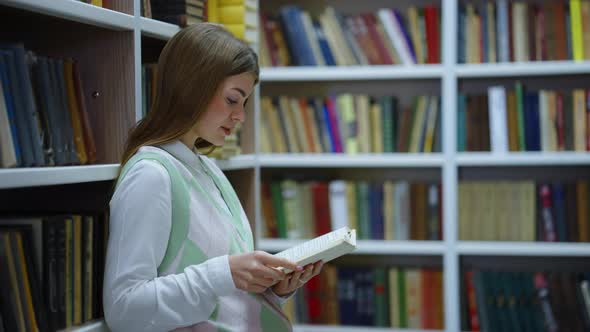 Woman Leaning on Bookcase and Reading Book