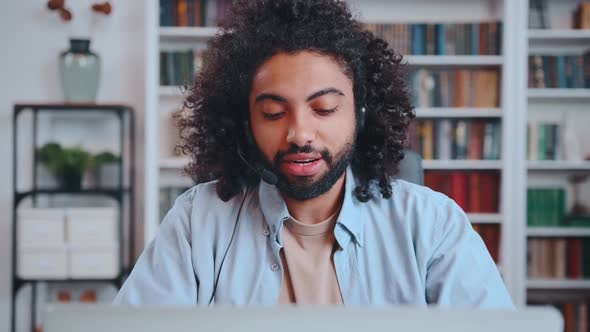 African American Man Talks Video Call Using Headset with Microphone Via Laptop