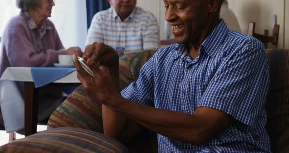 Senior man using mobile phone with his friends sitting in background 4k