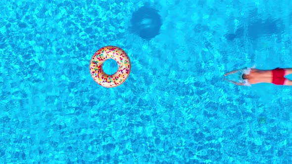 Top Down View As a Man Dives Into the Pool and Swims with Inflatable Donut