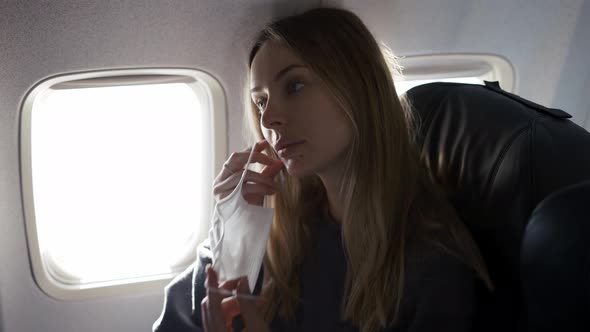 Blonde Woman Putting on Protective Mask on Plane