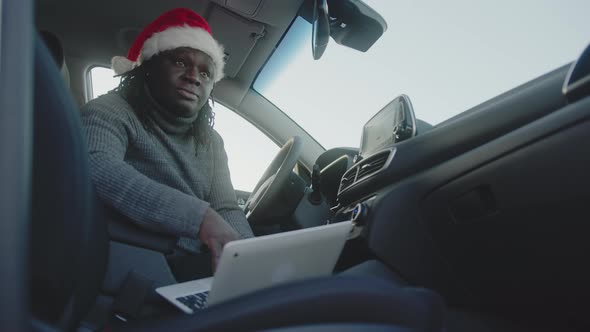 African American Black Man with Christmas Hat Using Laptop in His Car