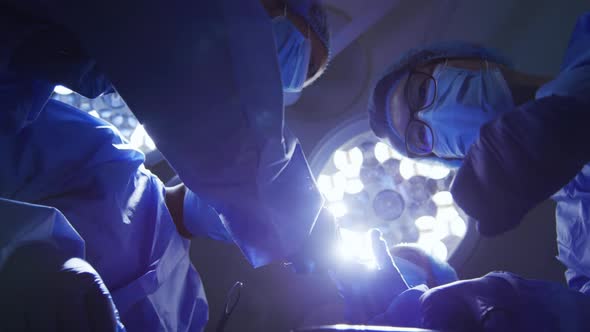 Surgeons wearing face masks holding surgical instruments in operating theatre