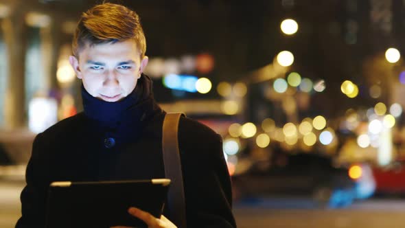 Attractive Man Uses a Tablet in a Night City