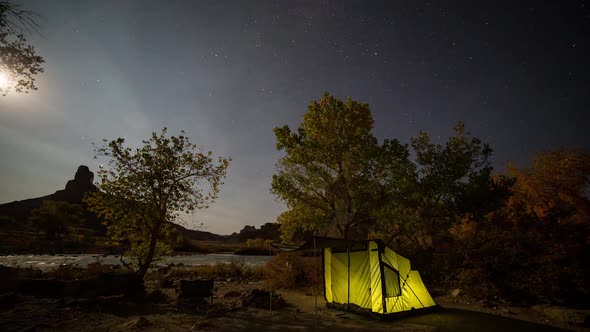 Campsite time lapse at night as tent glows and fire lights up the trees