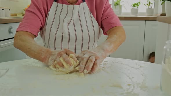 Grandmother is Preparing Dough in the Kitchen