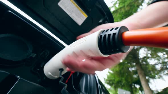 Man Removes Charging Cable From a Electric Car Socket. Charging of Electric Car