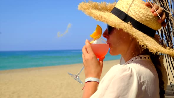 Woman on the Beach Drinks a Cocktail