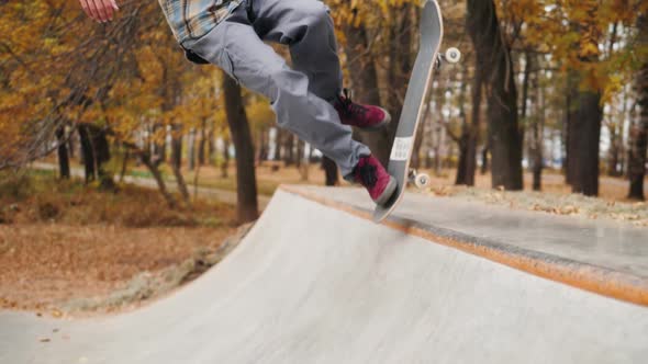 Skater Practicing in the Autumn Concrete Skate Park Making Tricks and Rides in Ramp