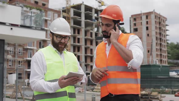 Engineer Speaks on Mobile Phone on Construction Site and Checks the Work of the Worker. Builder