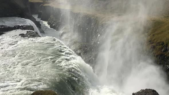 Majestic side view looking at waterfall. Water is making a lot of vapor when crushing down the cliff