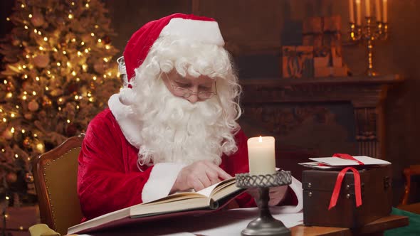 Workplace of Santa Claus. Cheerful Santa is working while sitting at the table.