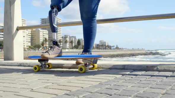 Low section of disabled woman standing with skateboard on promenade 4k