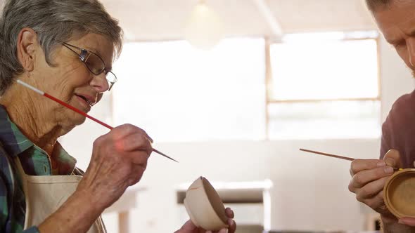 Male and female potter painting pots