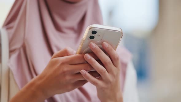 A cropped view of an arabian woman wearing national hijab is using her mobile