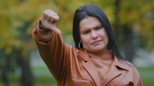 Headshot Overweight Young Woman Stands Outdoors Looking at Camera Hispanic Angry Girl Showing Thumbs