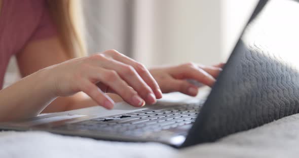 Female Hands Typing on Laptop Keyboard on Bed at Bedroom Close Up View