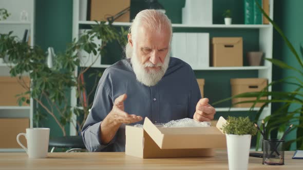 Aged Older Man Unpacking Carton Box Satisfied with Internet Store Purchase