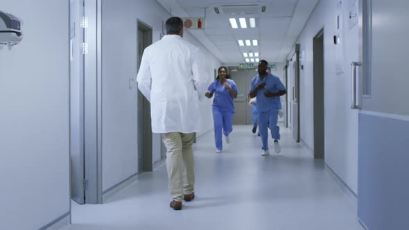 Diverse group of male and female doctors running urgently through hospital corridor